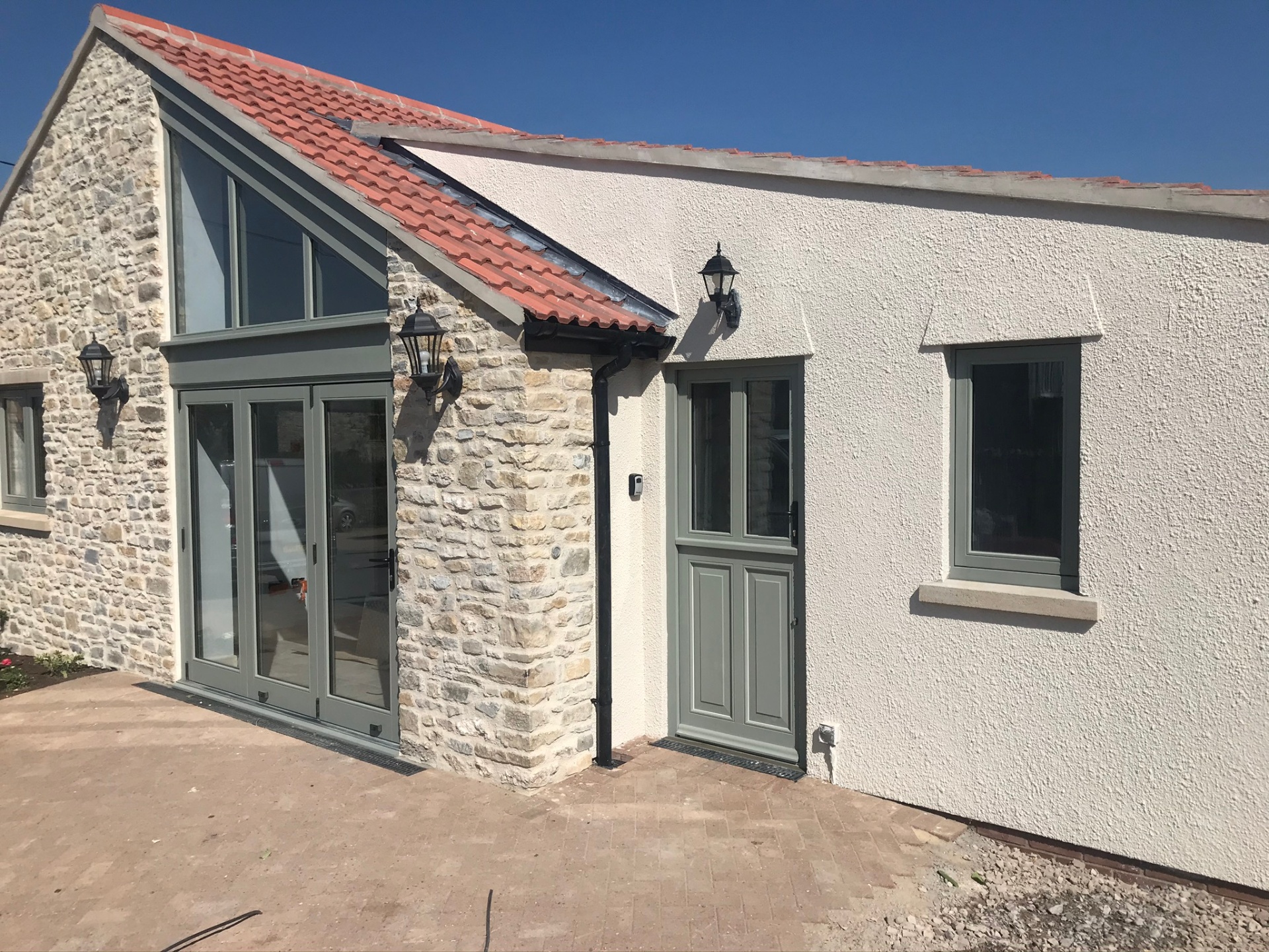 Rear elevation showing rendered wing and stone-built extension under a clay tile roof
