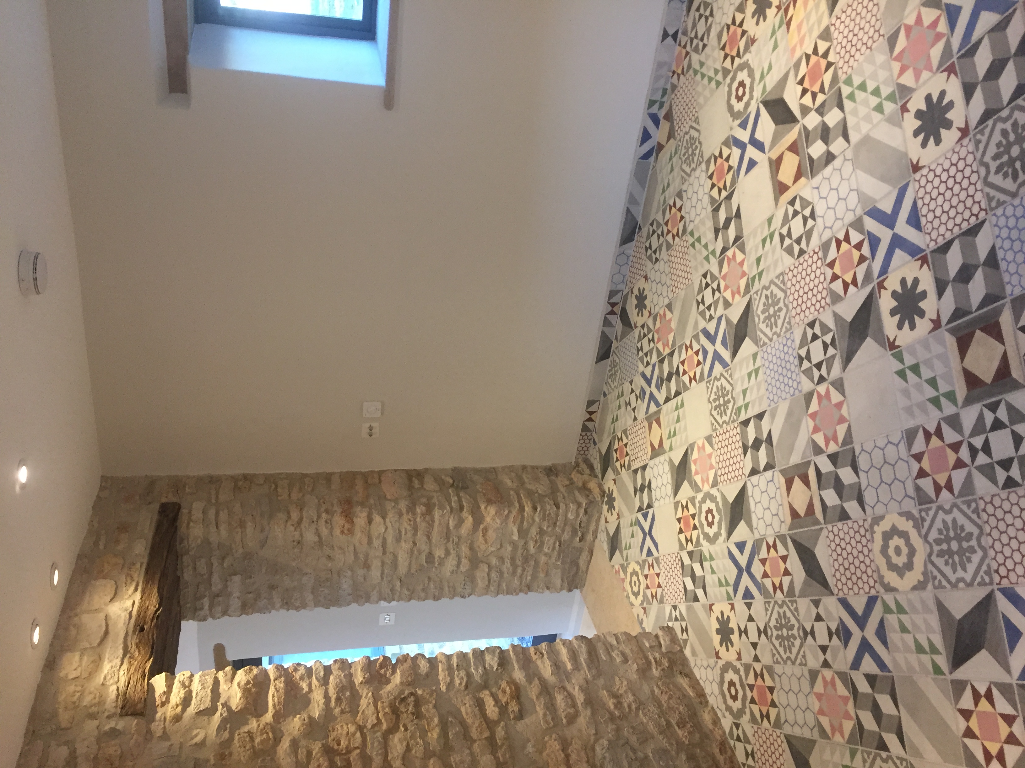 Entrance hall with patterned encaustic floor tiles, exposed stone wall and oak lintel