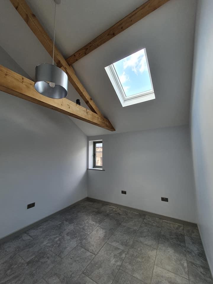 Vaulted bedroom with exposed timber beams and rooflight