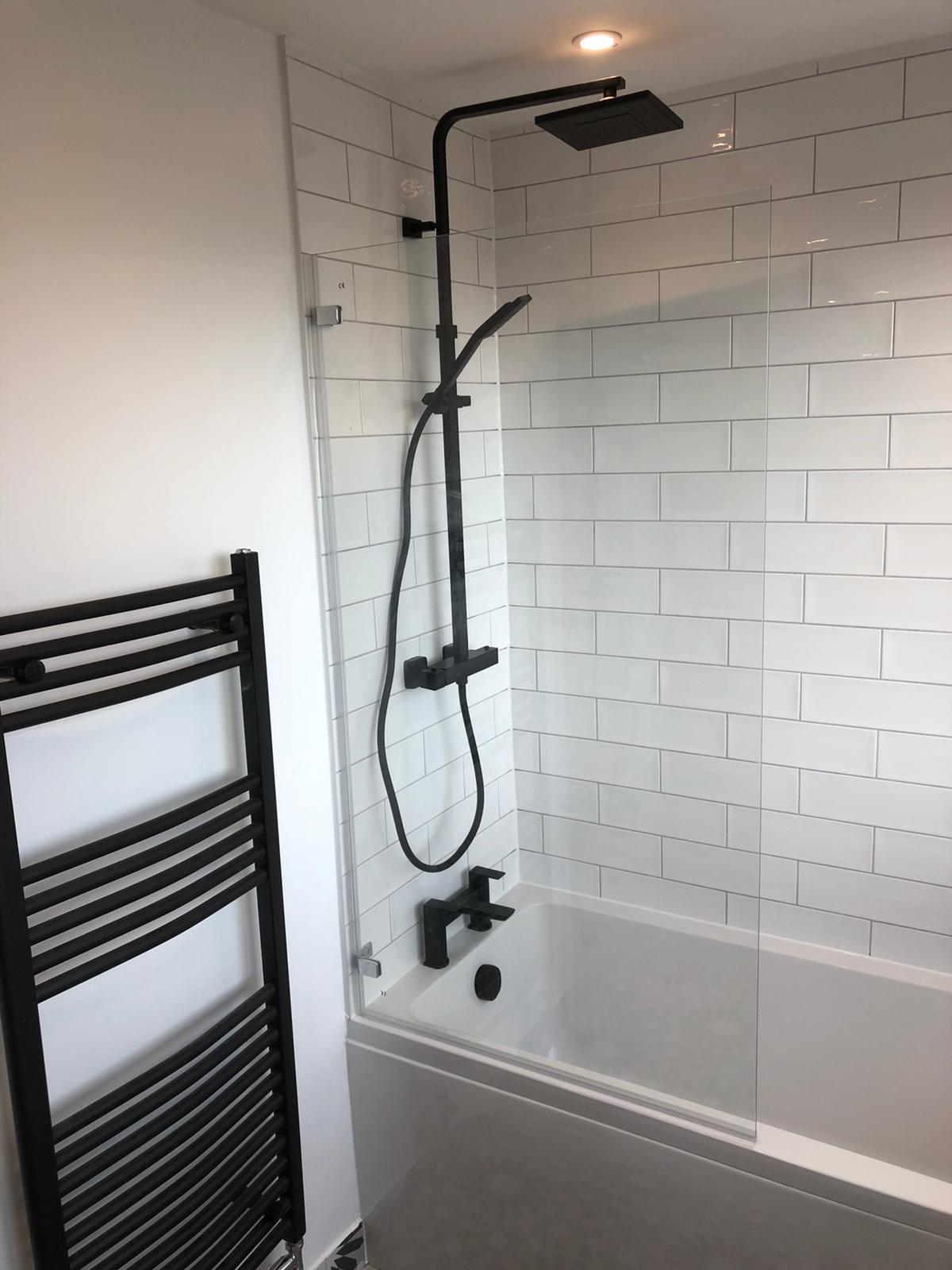 White metro-tiled bath and shower with matte black fittings