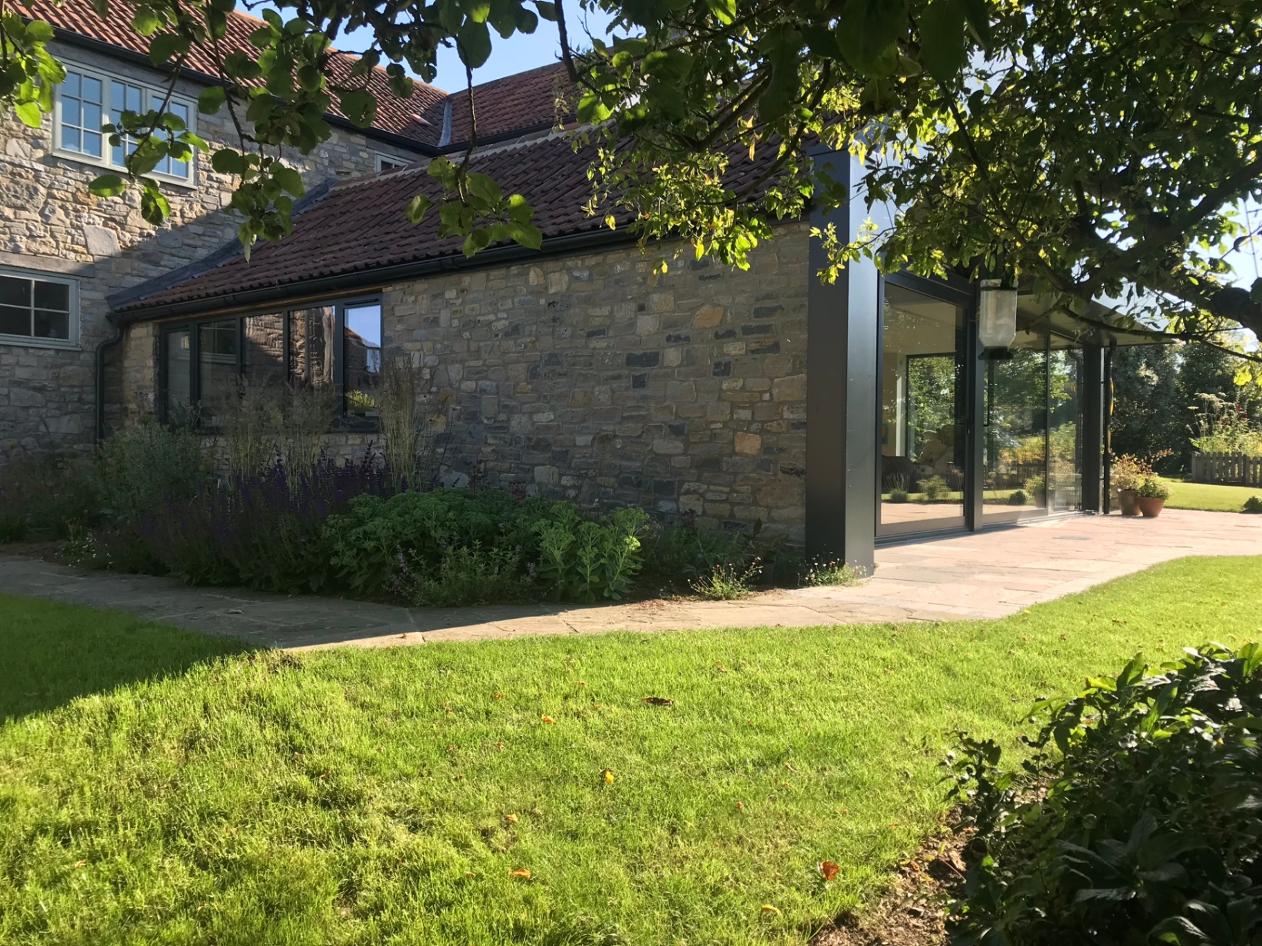 Rear elevation with stone extension and full-height corner glazing onto the garden