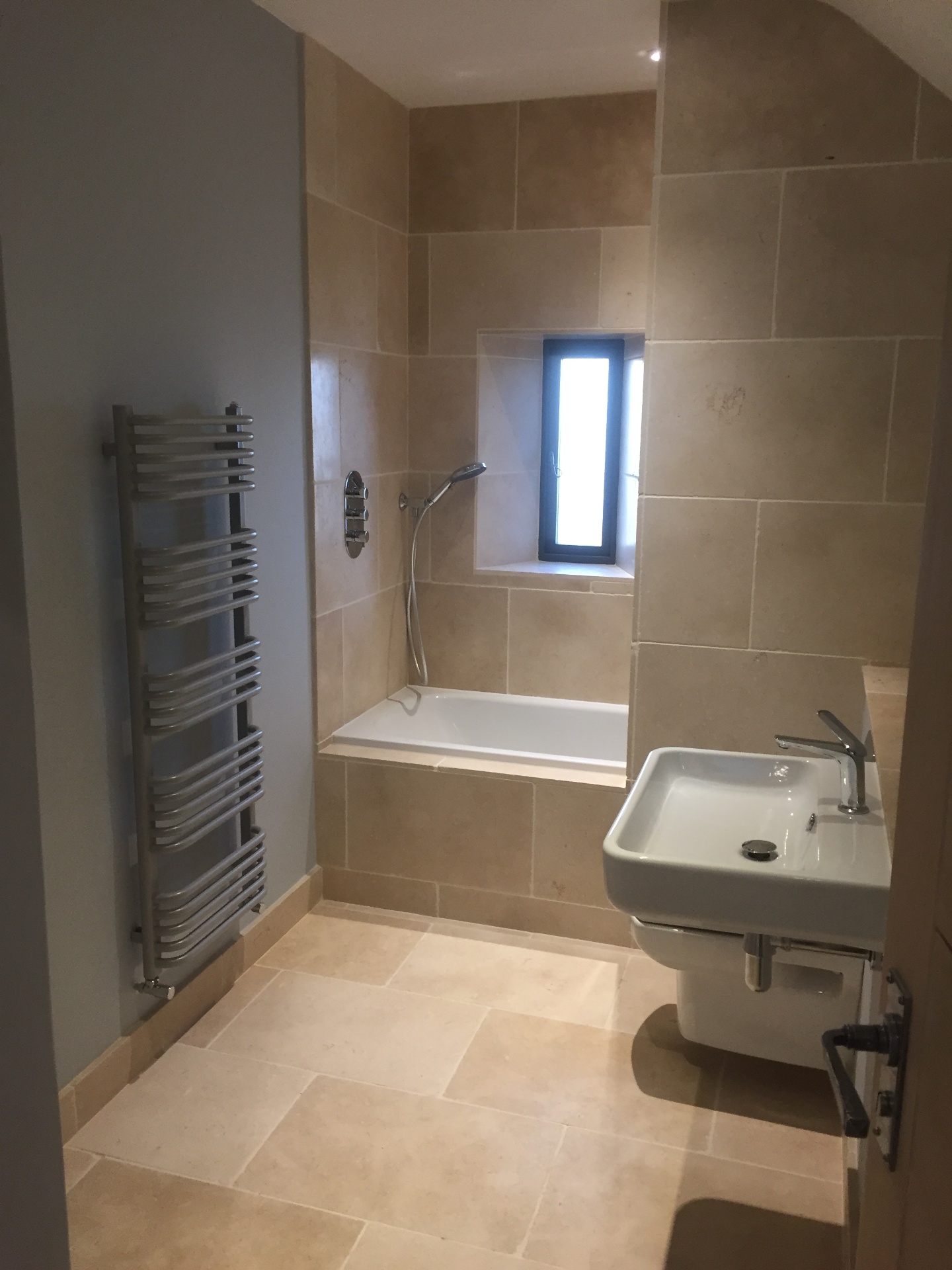 Traditional stone-tiled bathroom with chrome towel radiator