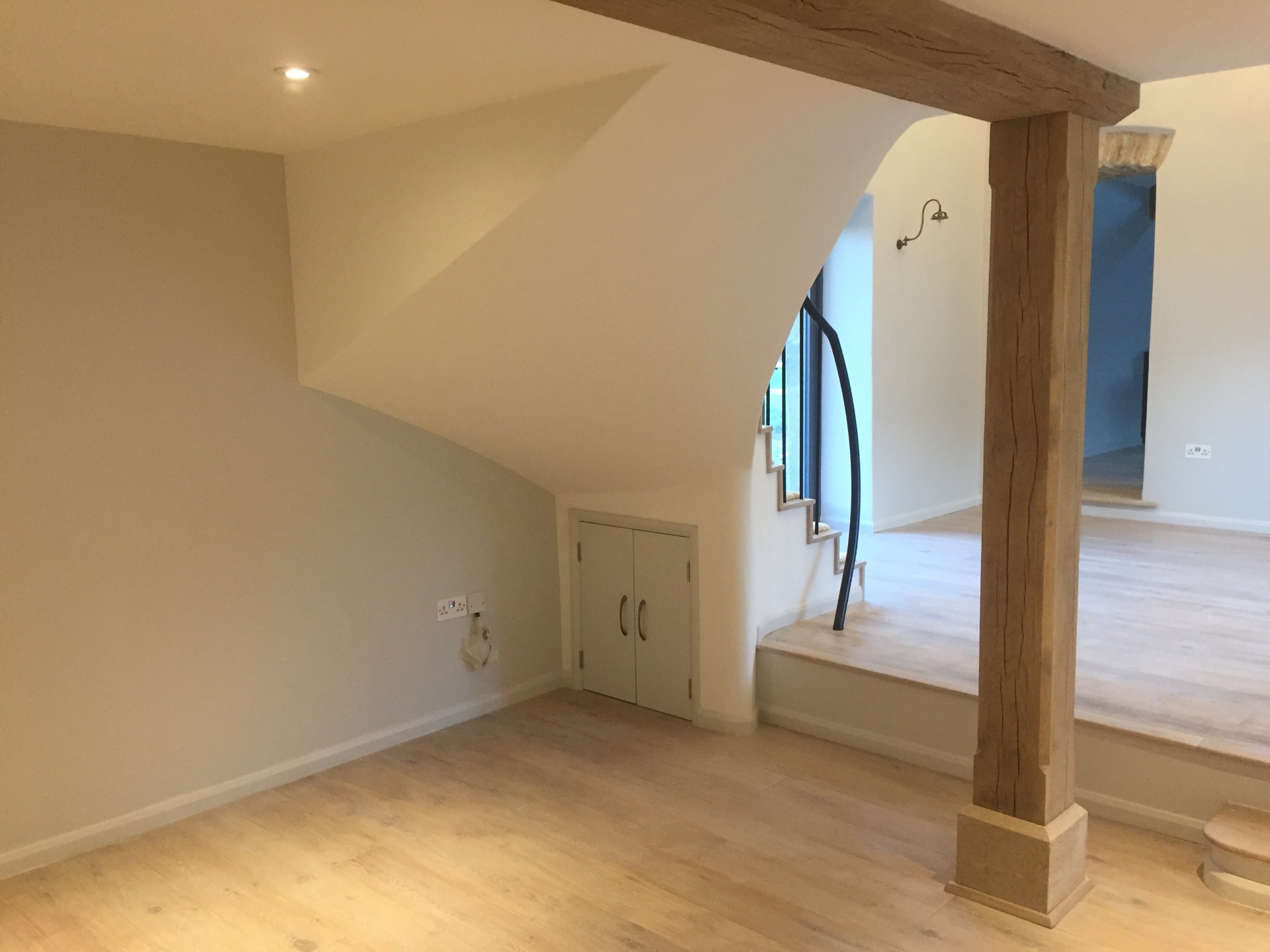 Interior with curved plaster stair, oak post and beam and light oak flooring