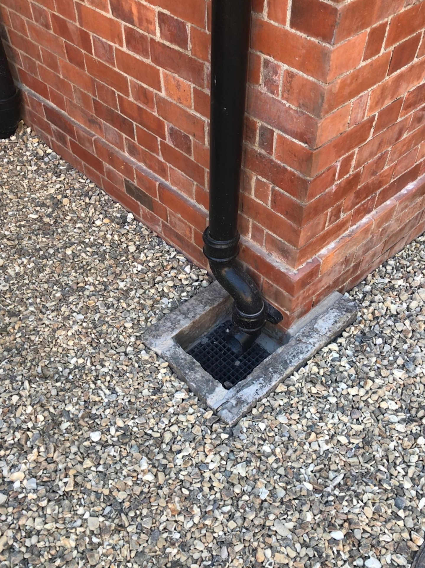 Cast-iron rainwater goods and gully detail at the base of the reclaimed brick wall