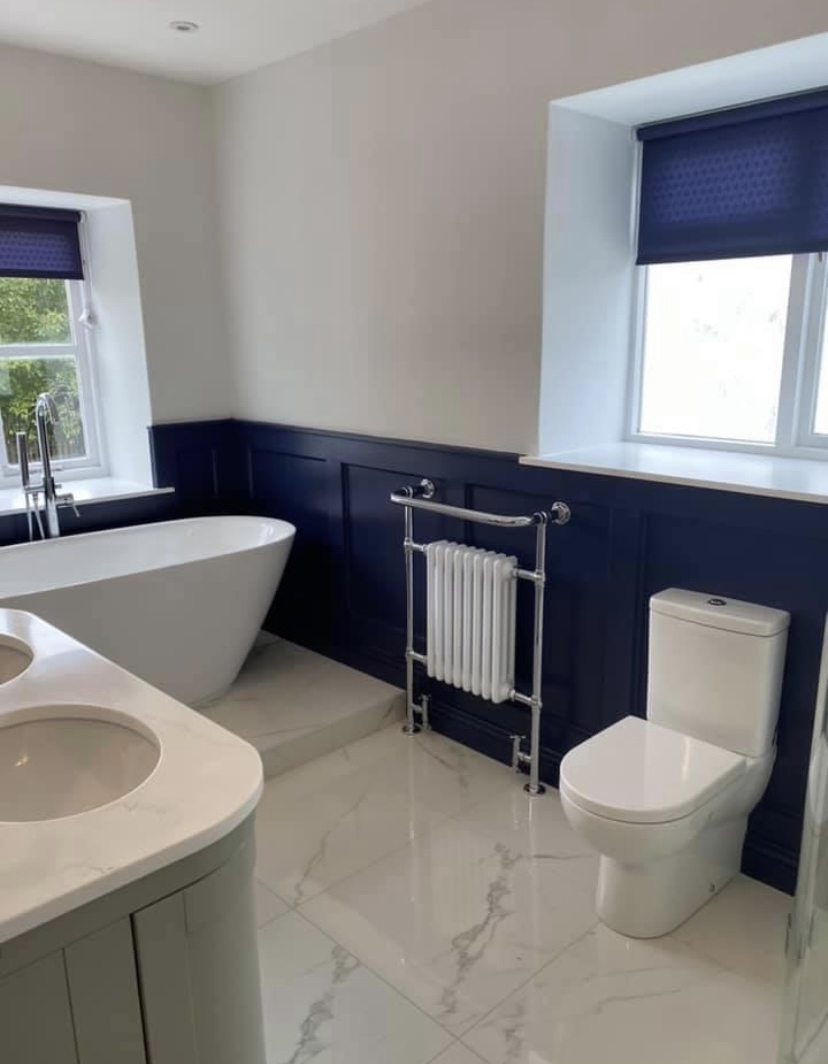 Classic bathroom with navy panelling, freestanding tub and marble floor