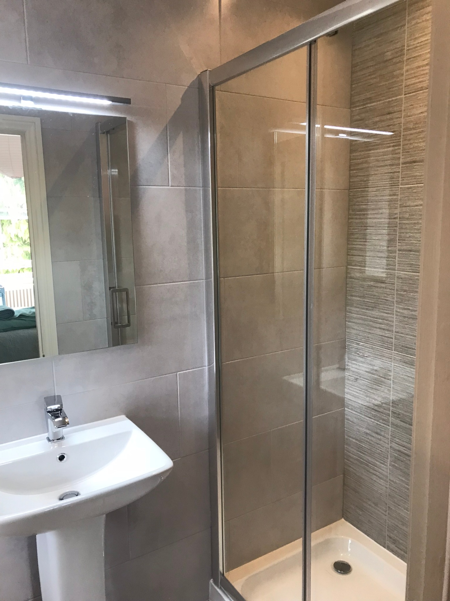 Compact ensuite shower enclosure with mixed stone tiling