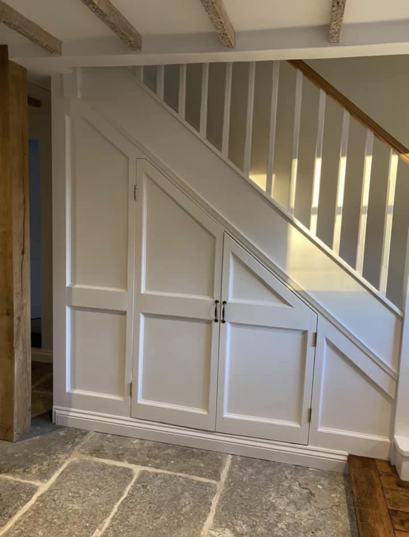 Bespoke understair cupboards with painted panelling alongside reclaimed flagstones