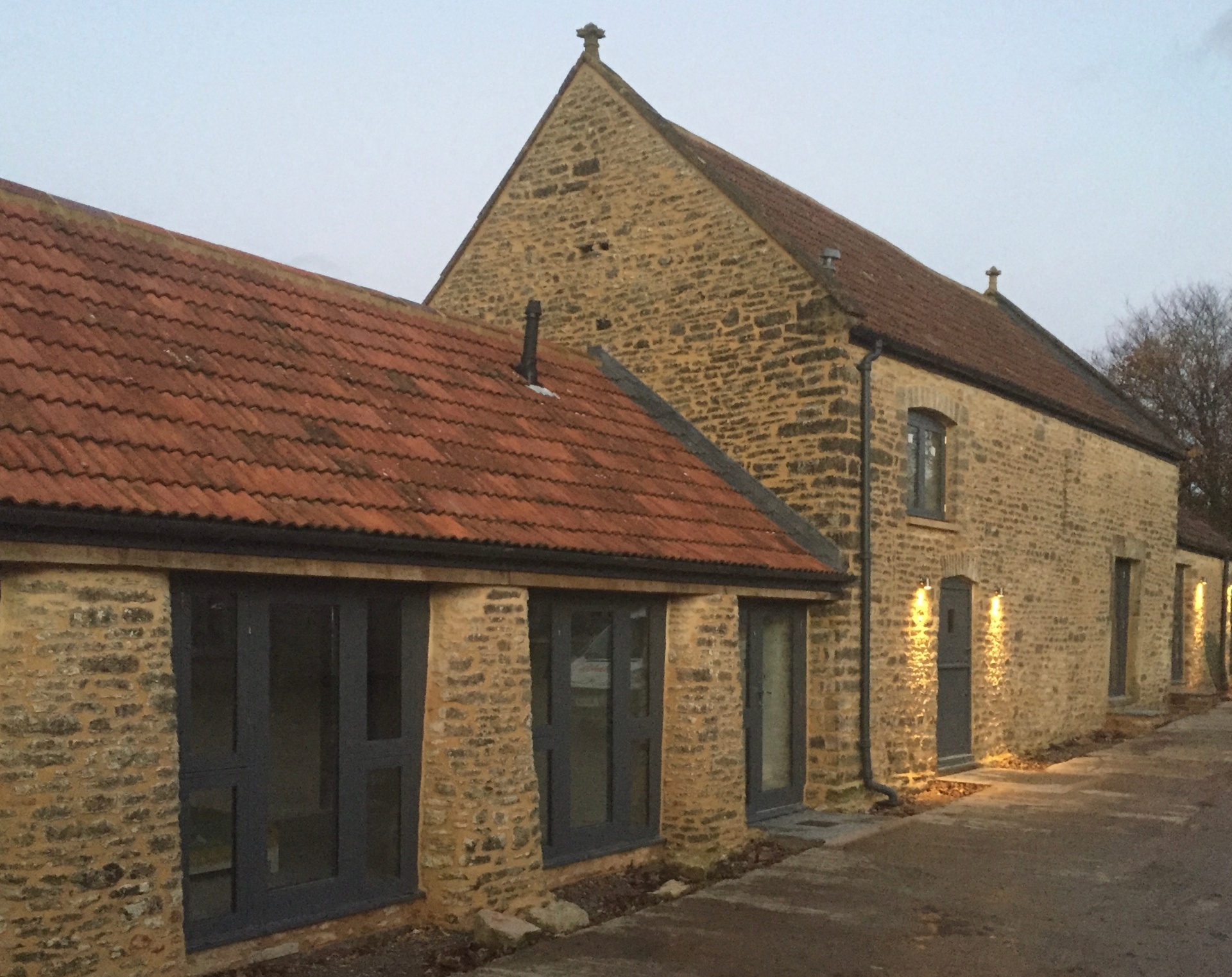 Completed stone barn conversion with clay tile roof and new grey-framed windows
