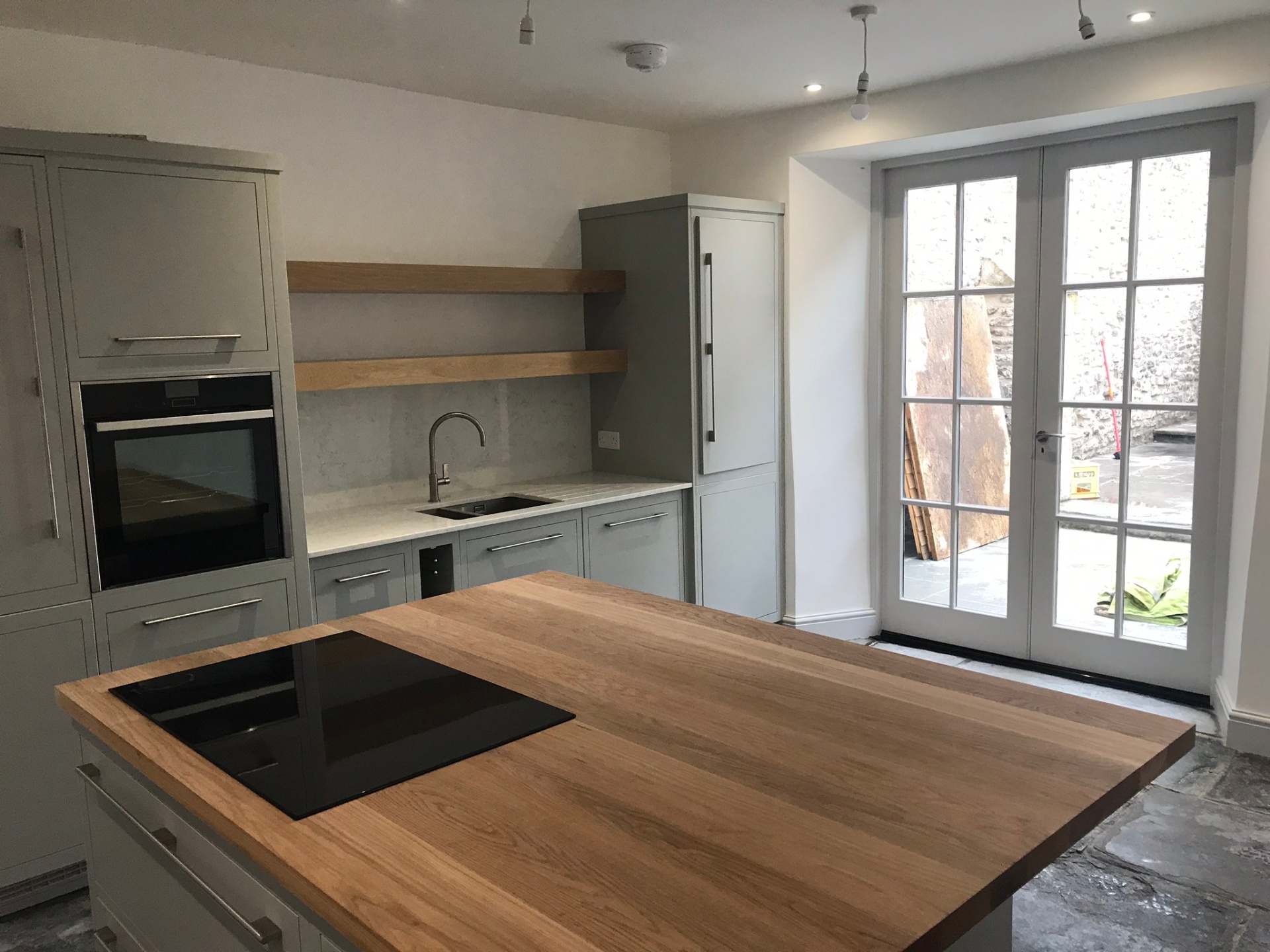 Painted shaker kitchen with oak island, quartz worktops and French doors opening to the courtyard