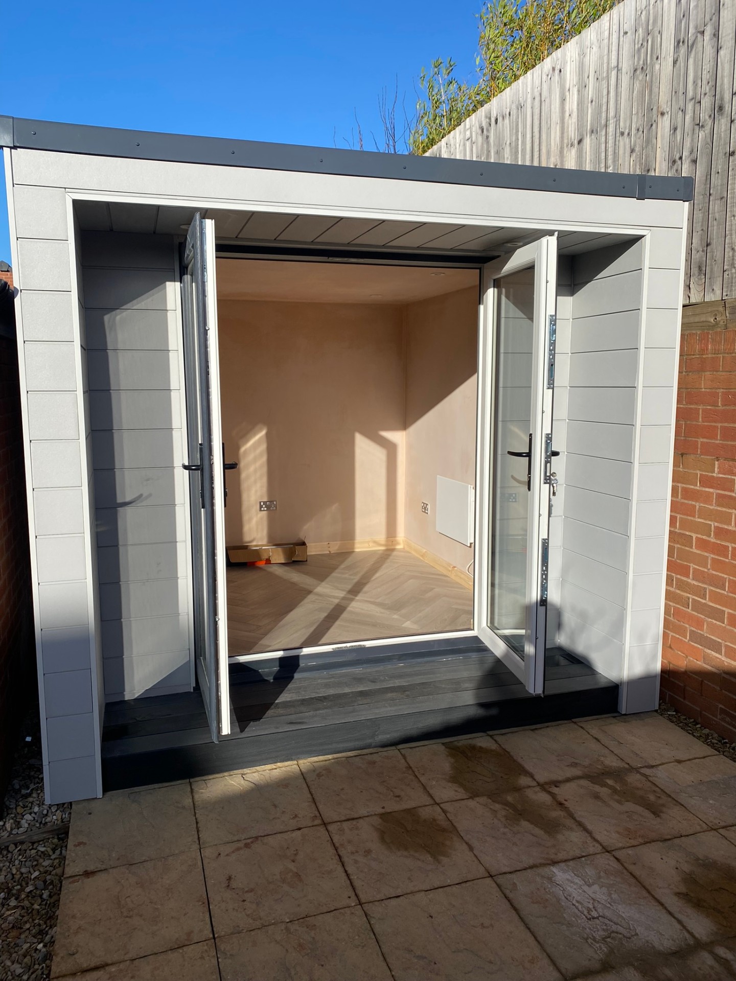 Garden office with doors open showing herringbone floor and plastered interior