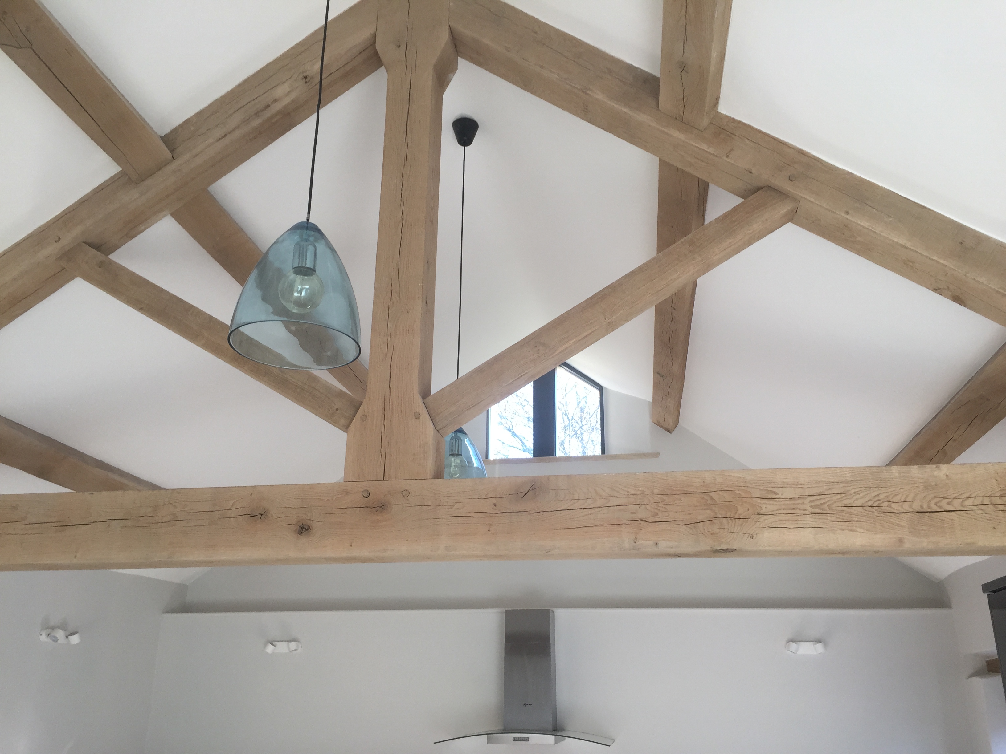 Vaulted ceiling with exposed oak trusses and glass pendant lights above the kitchen
