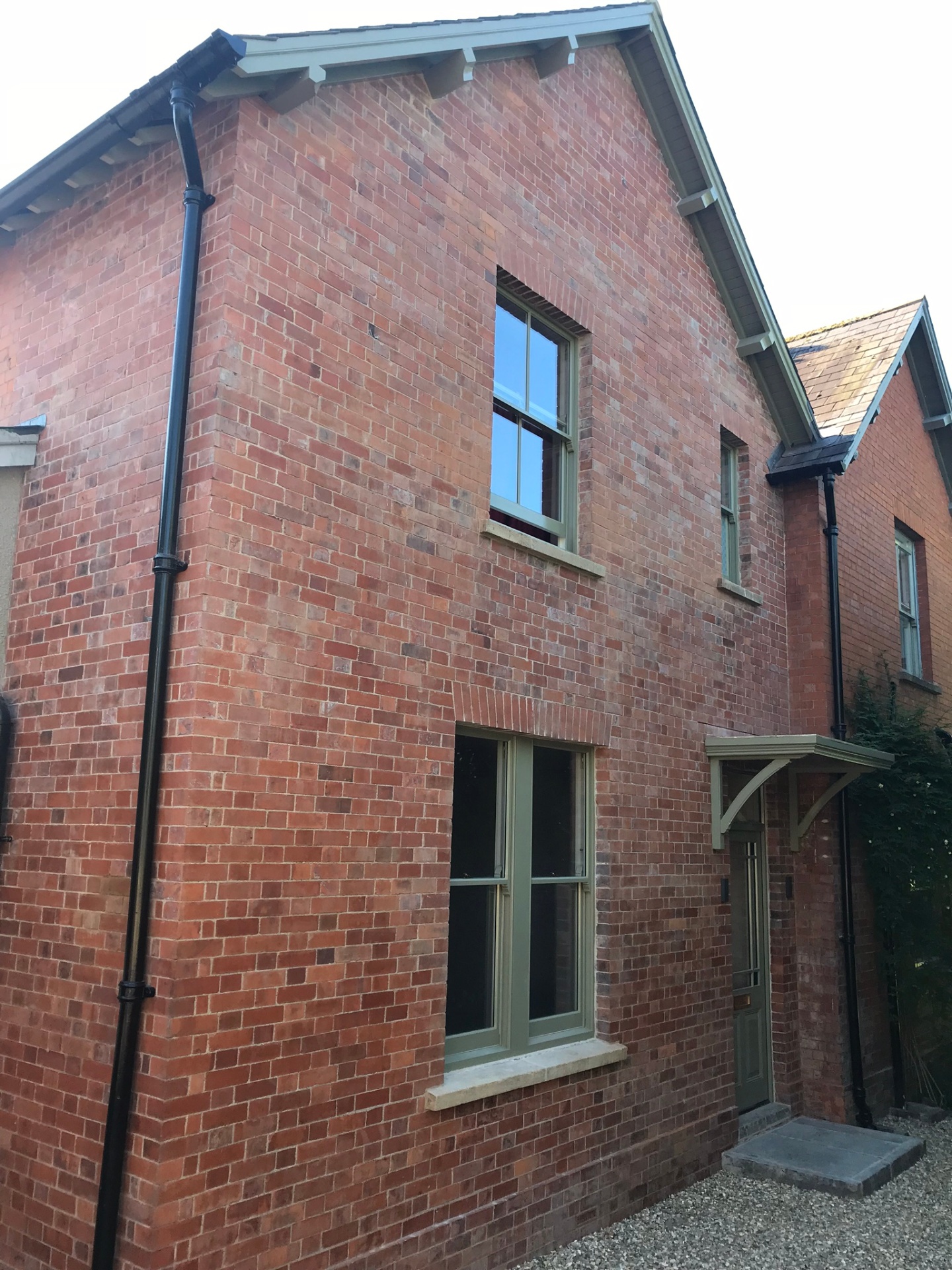 Full view of the rebuilt gable with new sash windows and timber porch canopy