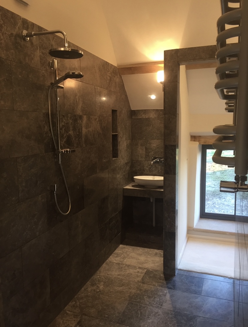Vaulted ensuite with dark tiling, stone basin and rainfall shower