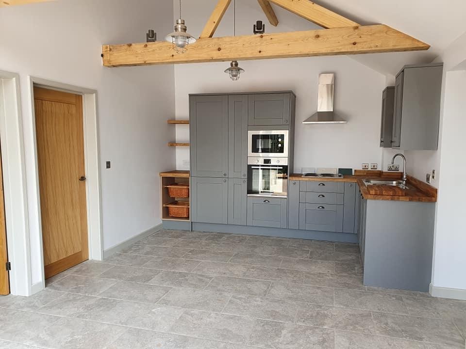 Kitchen with shaker cabinetry beneath exposed roof trusses