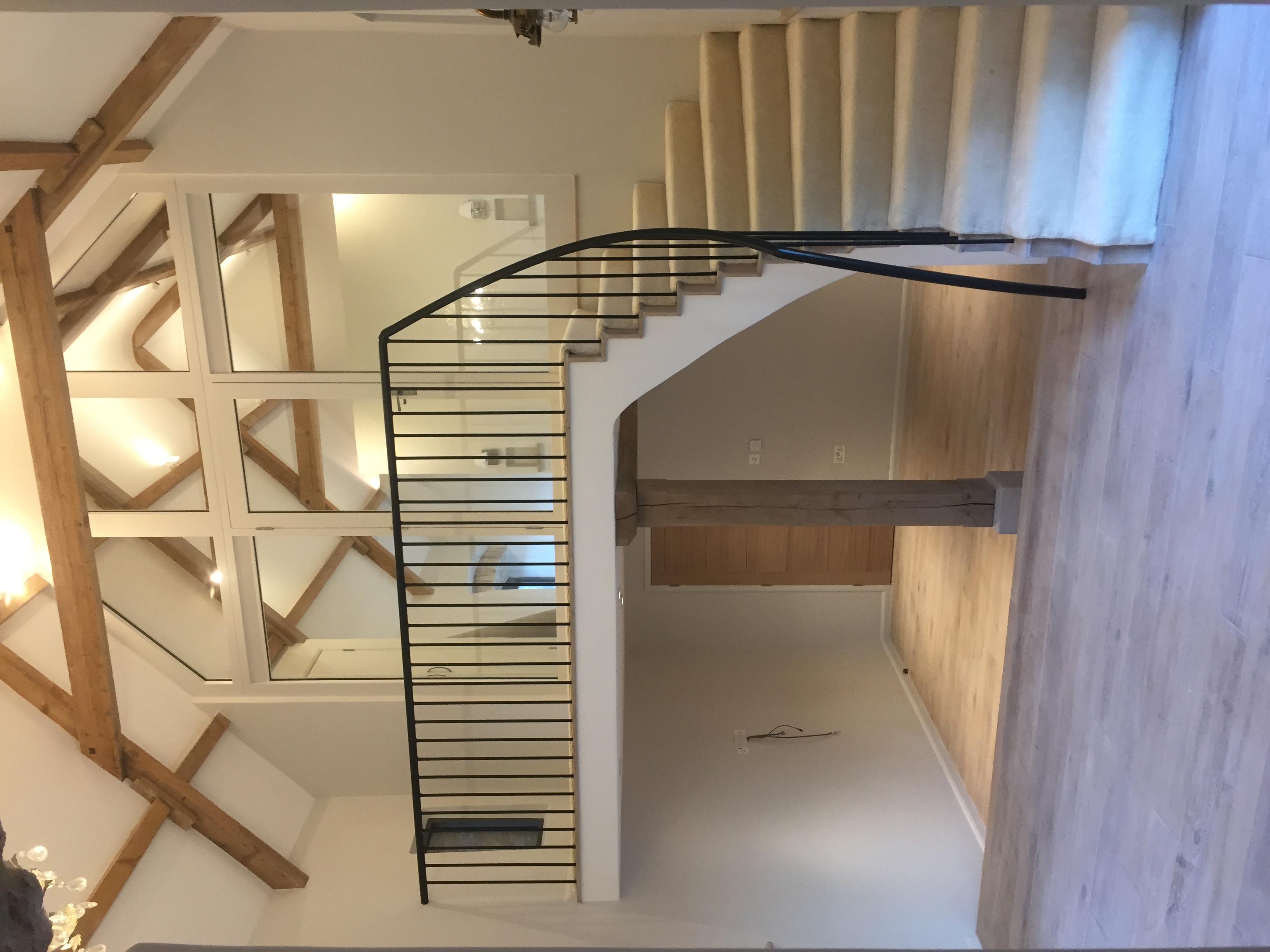Full-height curved staircase with iron balustrade, oak trusses and glazed gallery