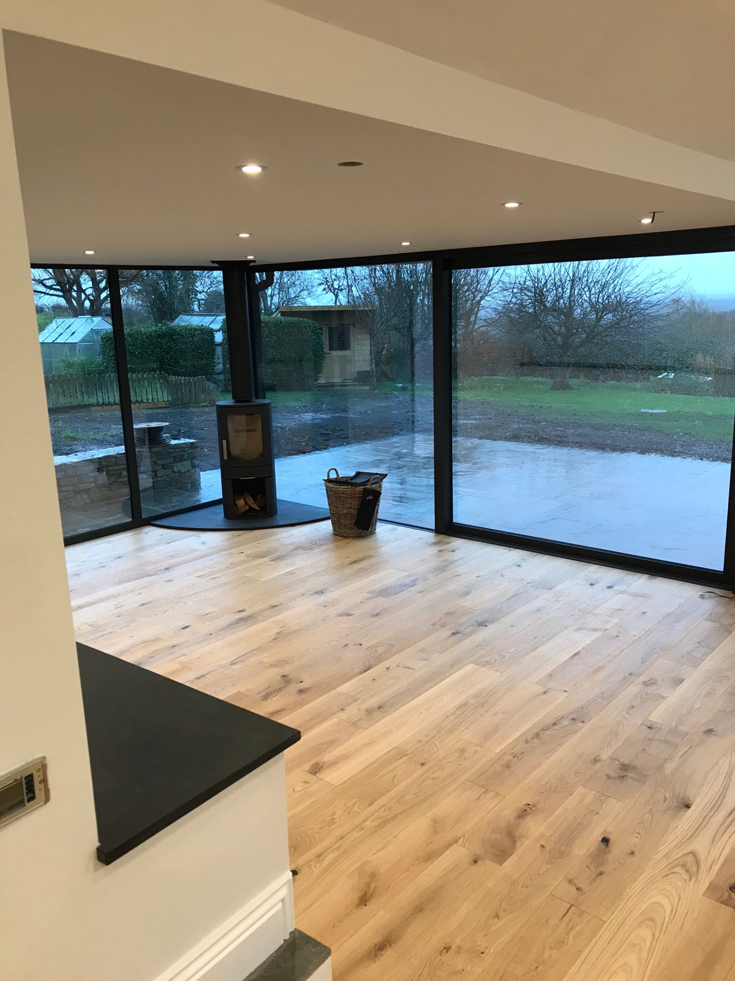 Open-plan living space with wood-burning stove and wraparound glazing