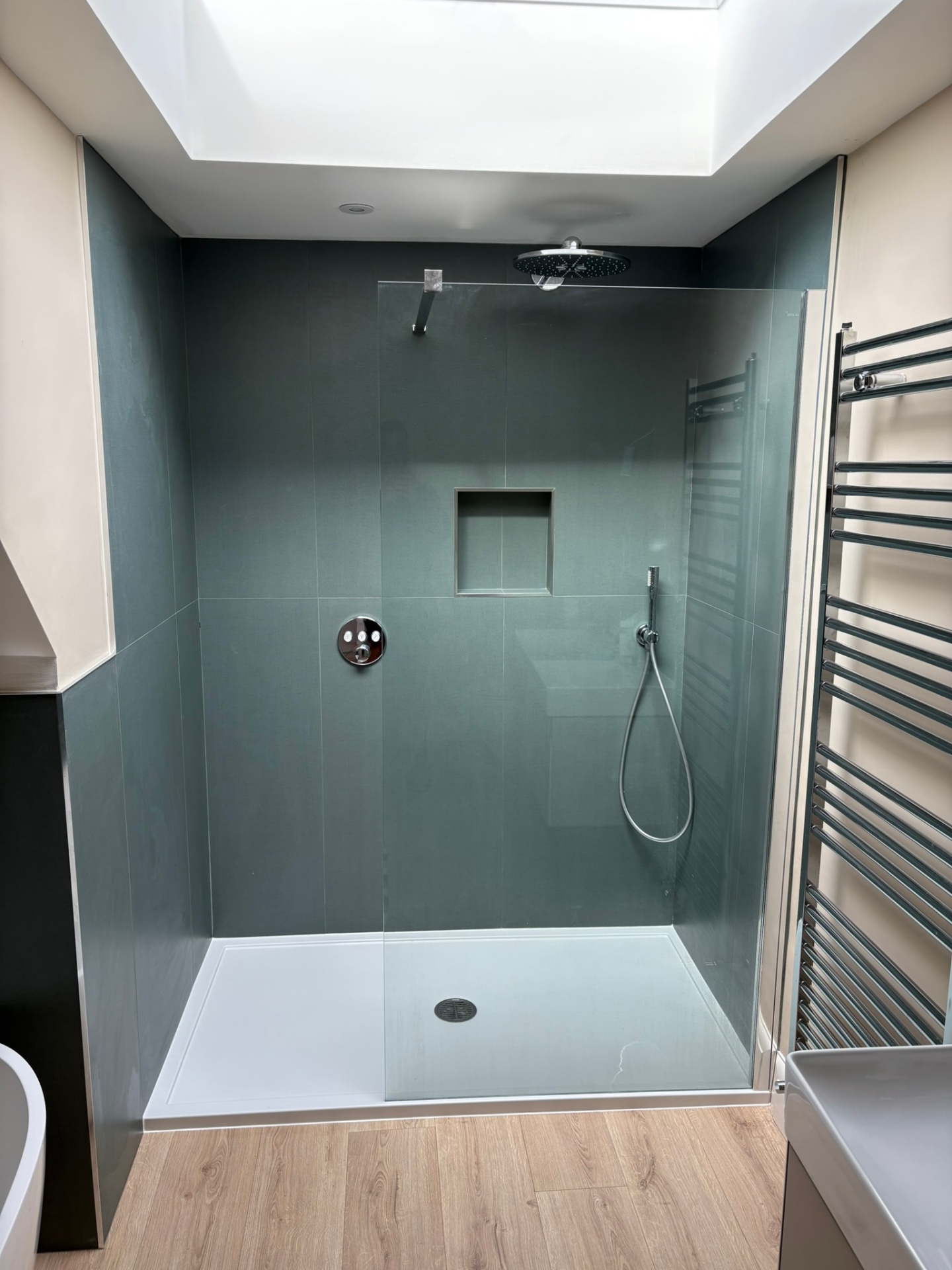 Walk-in wet room with deep green large-format tiles and skylight