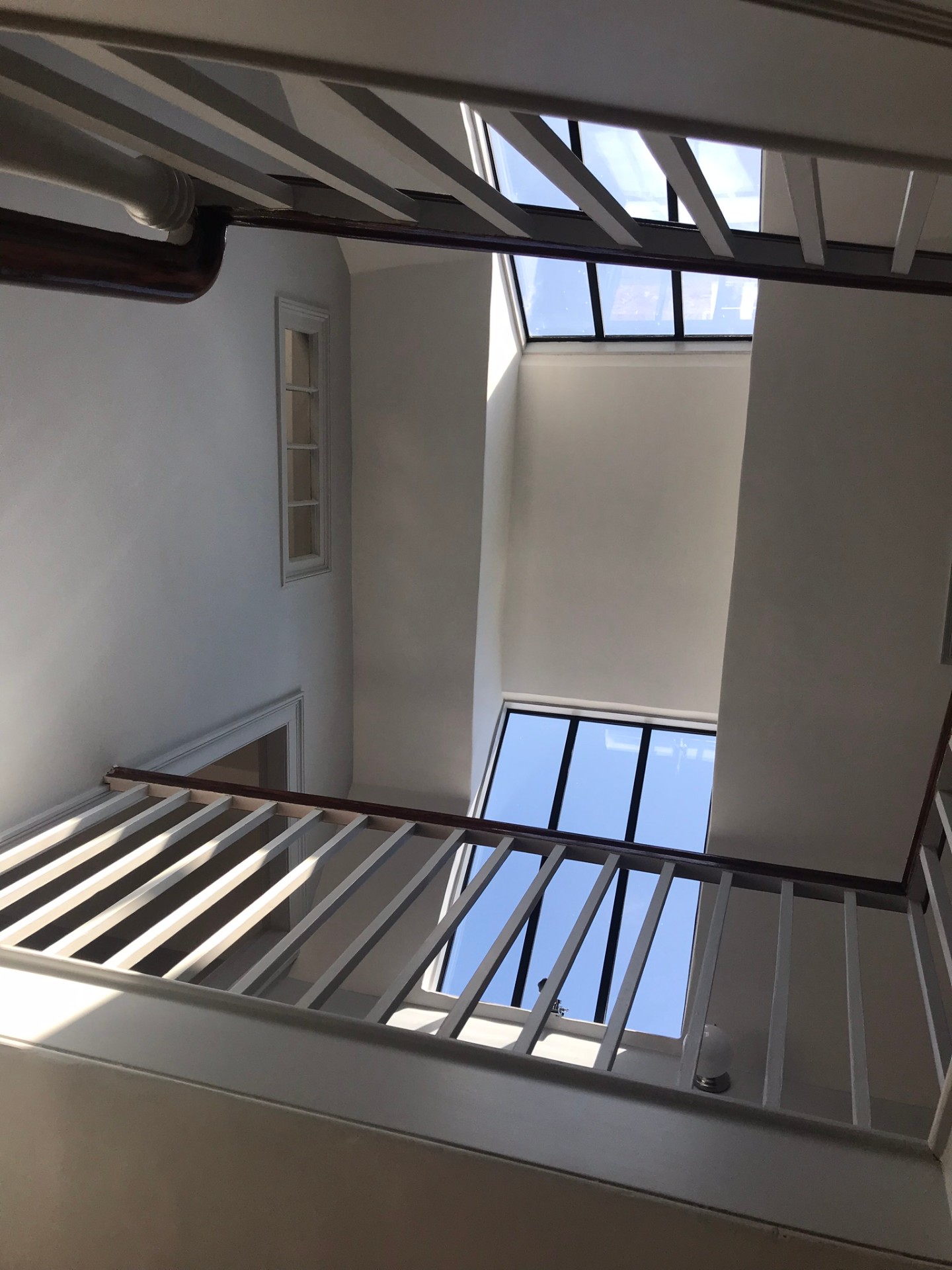 Restored stairwell looking up to roof lanterns and painted timber balustrades