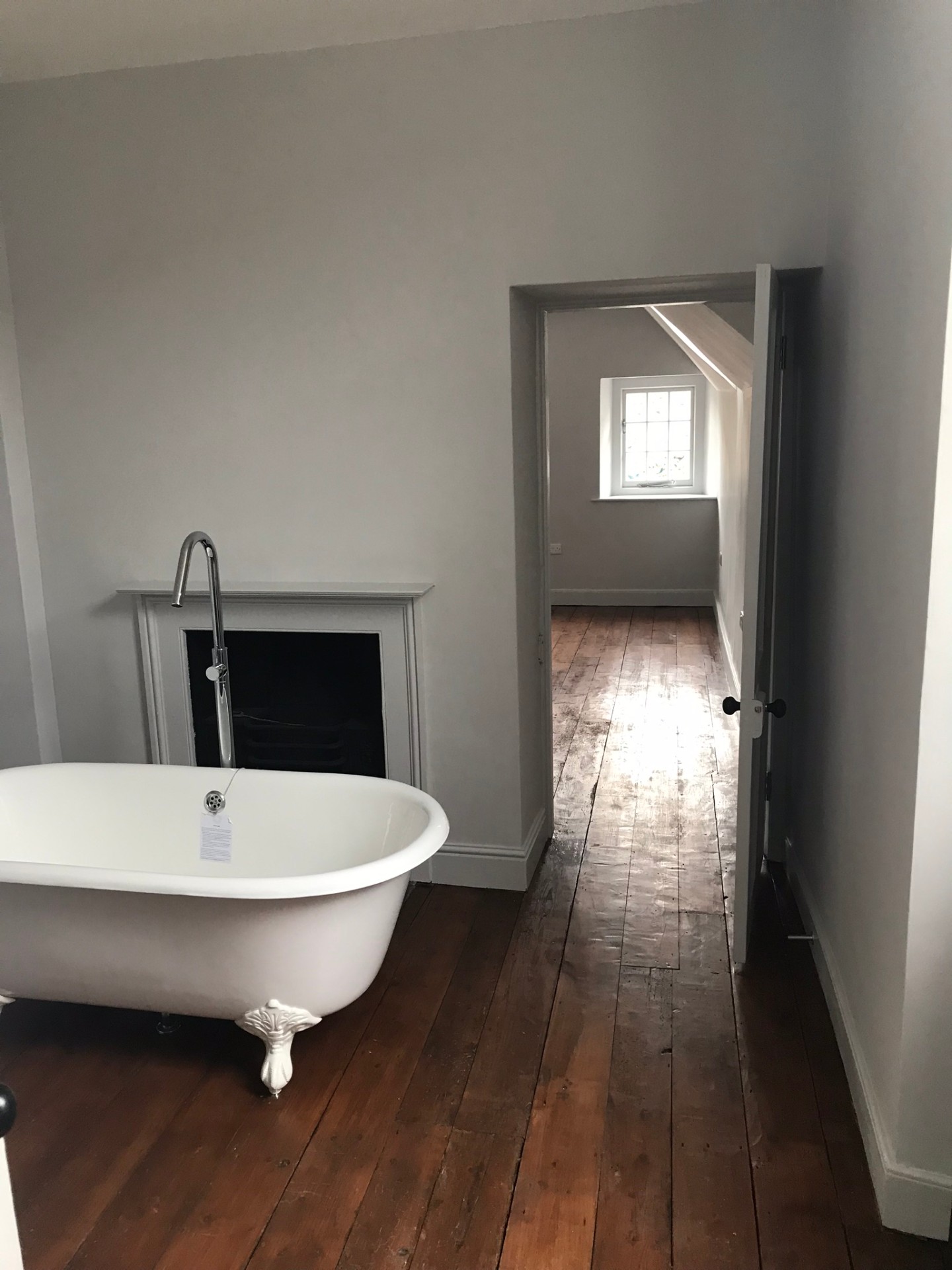 Bathroom with roll-top cast-iron bath, original fireplace and wide reclaimed floorboards