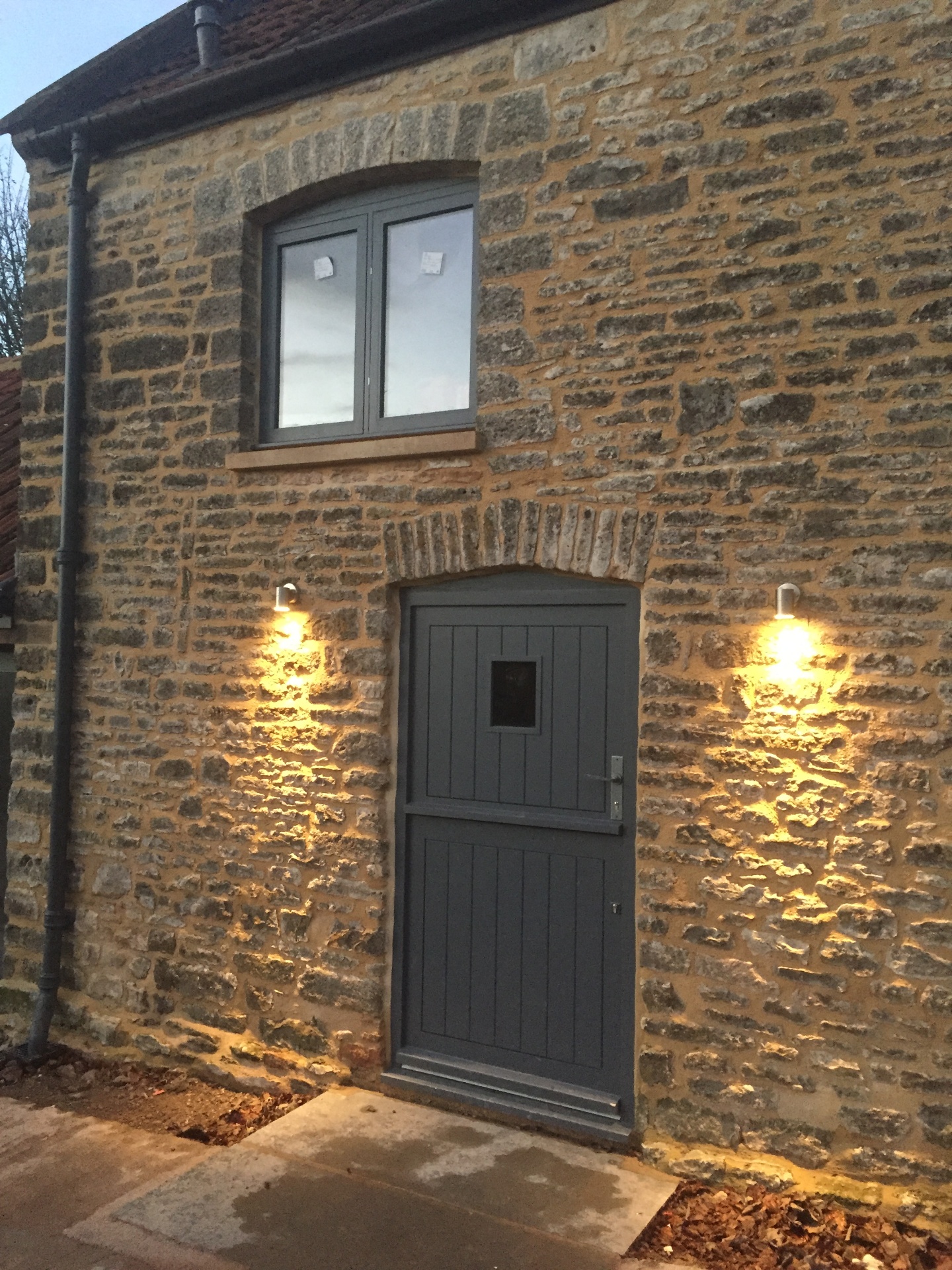 Restored stone elevation with new arched doorway, grey joinery and external lighting