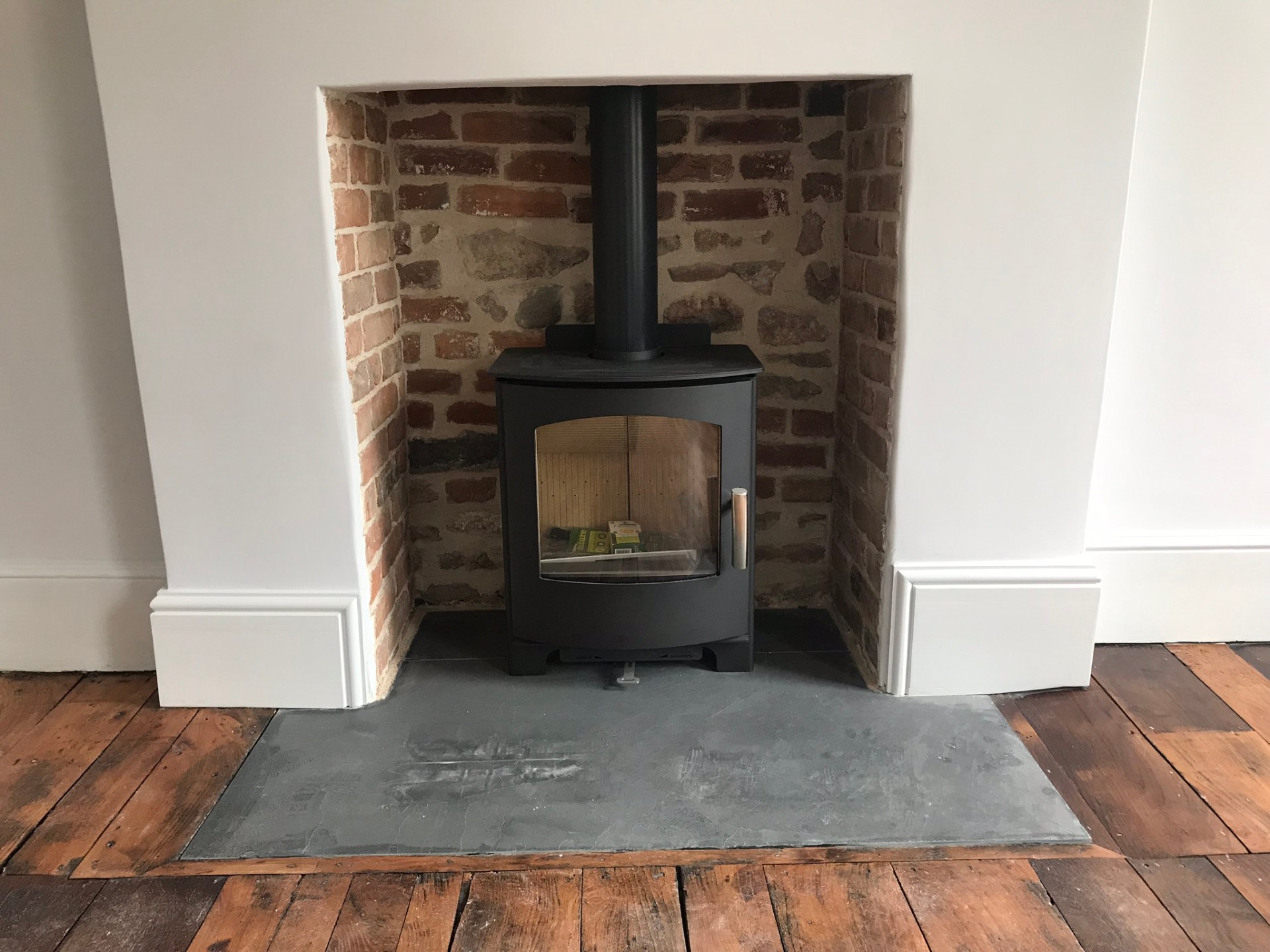 Reinstated fireplace with wood-burning stove, exposed brick reveal and original floorboards