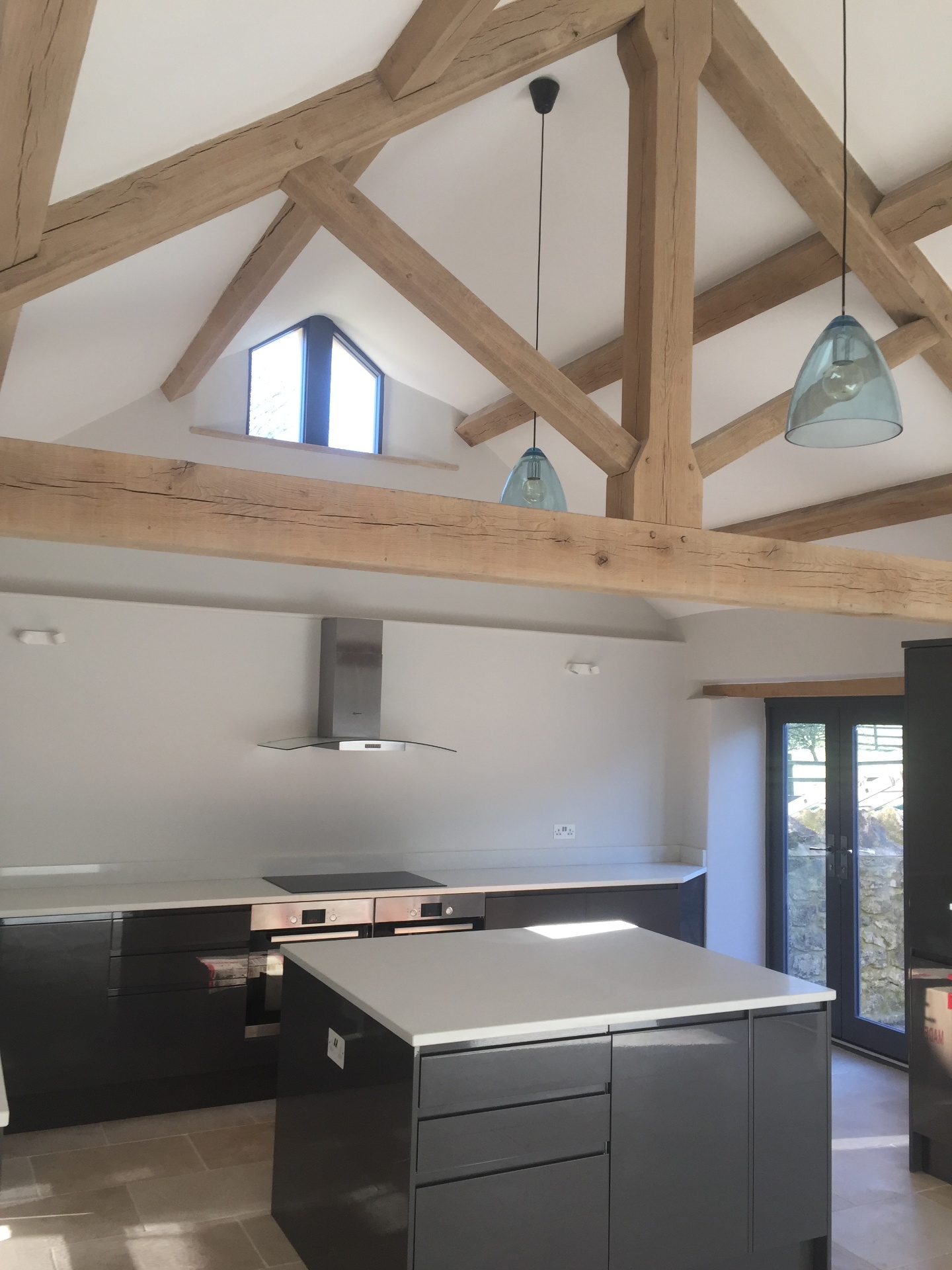 Open-plan kitchen with vaulted ceiling, exposed oak trusses and dark shaker units