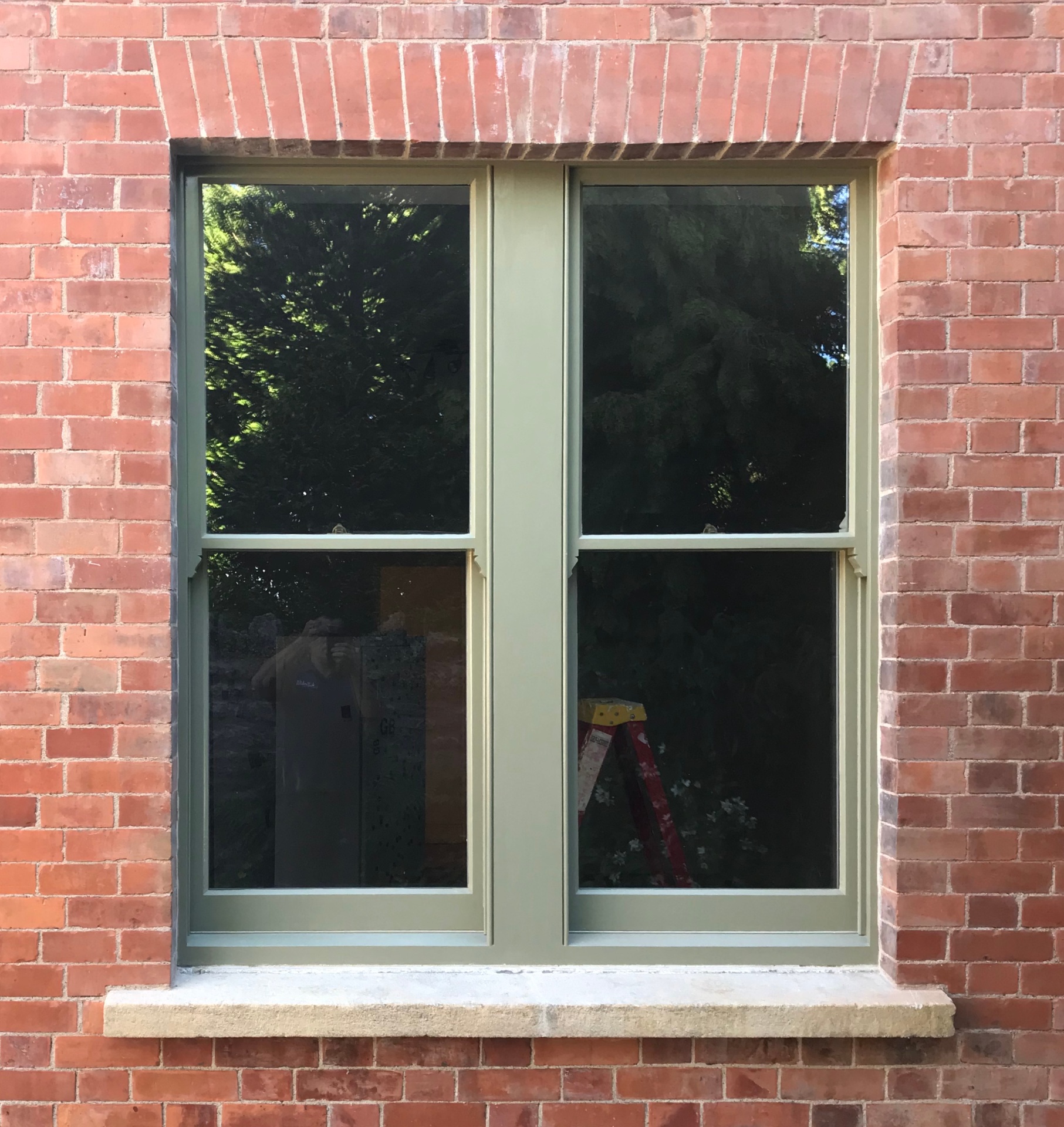 Detail of a traditional sash window with sage frame and stone sill