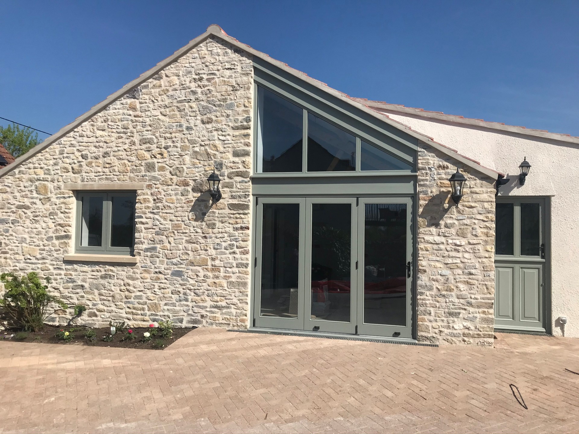 Sage-green bi-fold doors set into the stone gable end