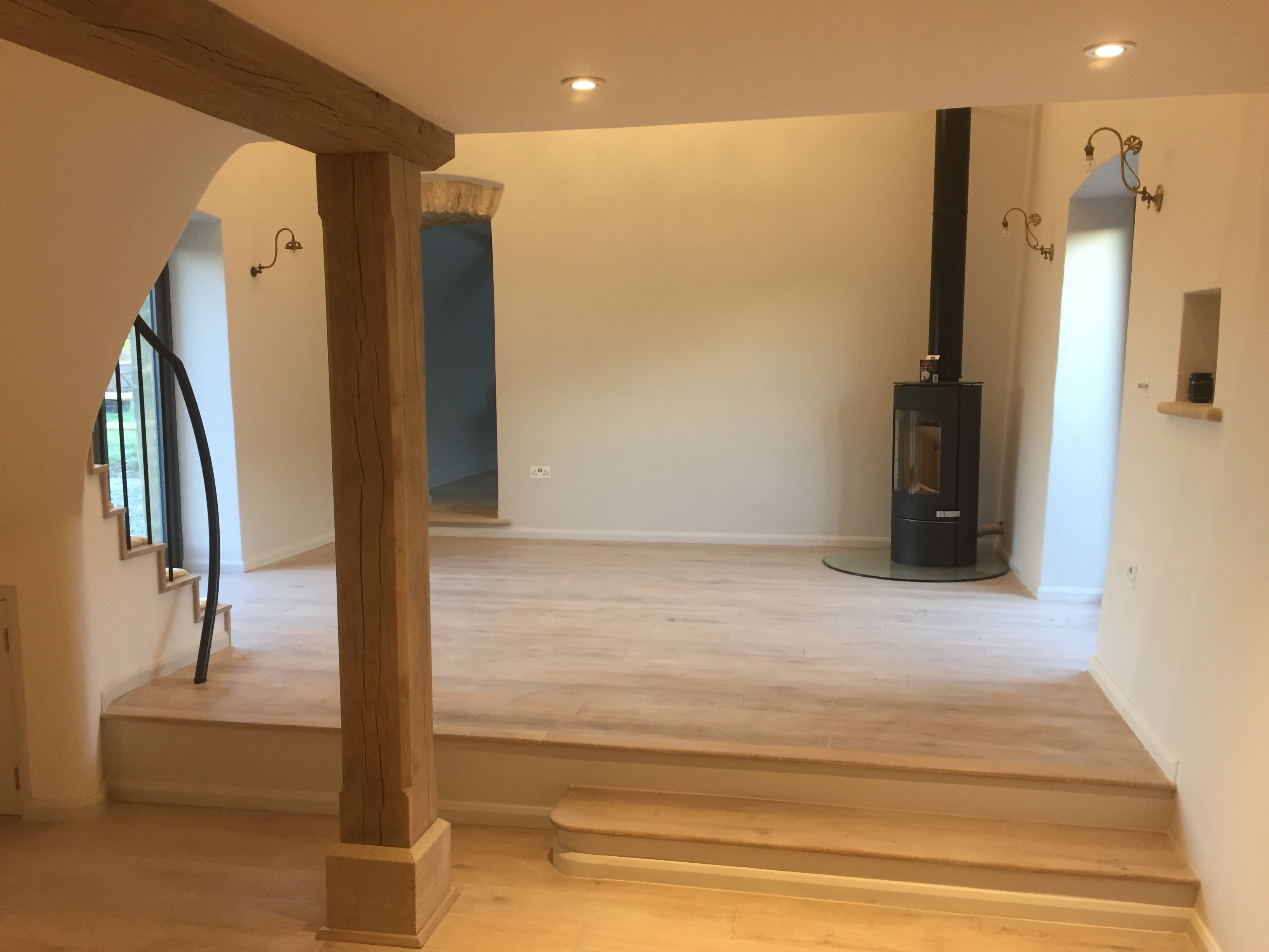 Split-level living room with wood-burning stove, oak post and curved staircase